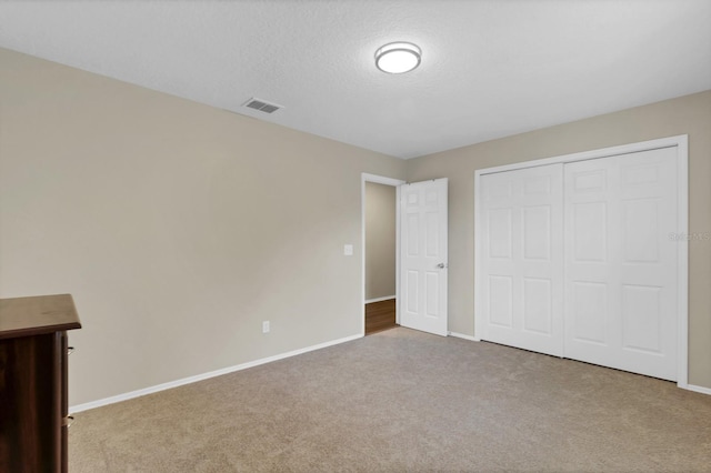 unfurnished bedroom with carpet, a closet, and a textured ceiling