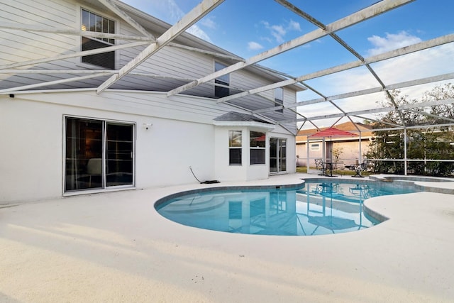 view of pool with glass enclosure and a patio