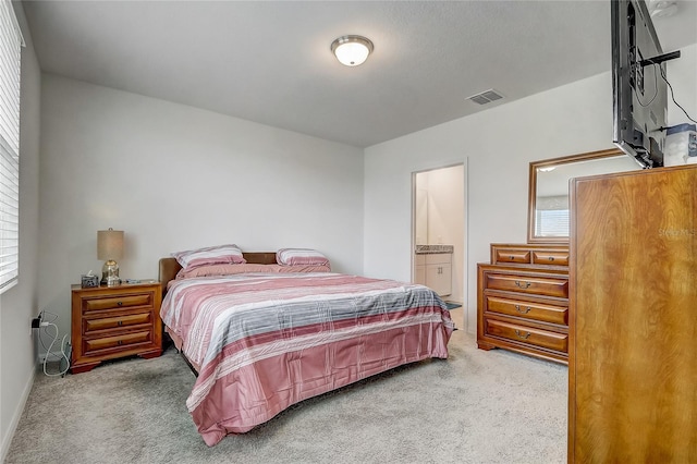 carpeted bedroom featuring ensuite bath