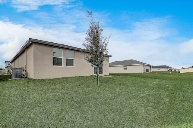 rear view of house with central AC unit and a yard