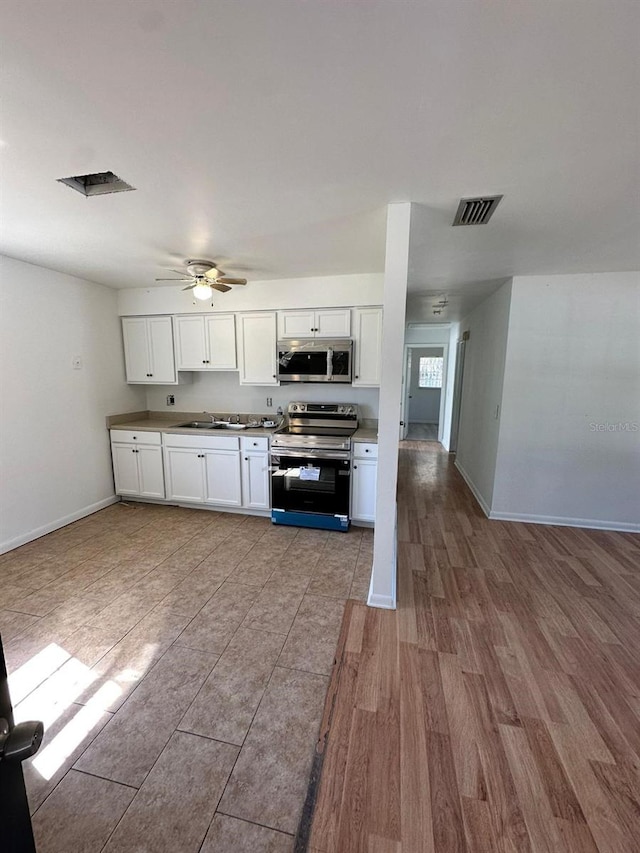 kitchen with white cabinets, appliances with stainless steel finishes, sink, light wood-type flooring, and ceiling fan