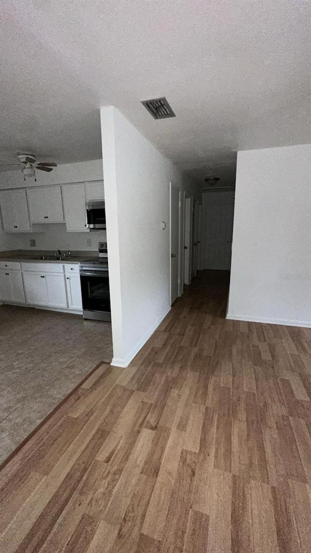 kitchen with white cabinets, hardwood / wood-style floors, appliances with stainless steel finishes, and a textured ceiling