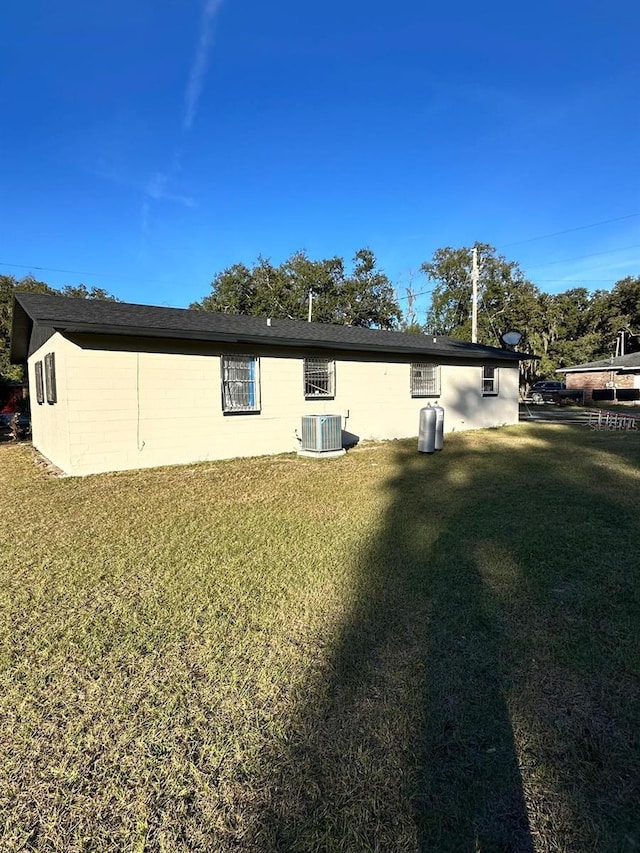 back of property featuring central air condition unit and a yard