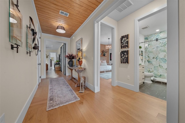 corridor featuring ornamental molding, wood ceiling, and light hardwood / wood-style floors