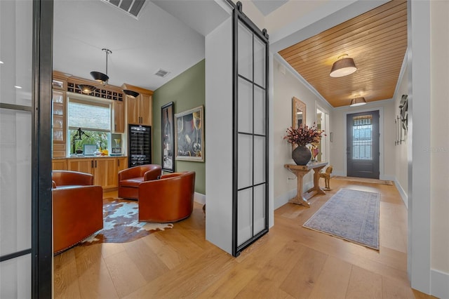 foyer with crown molding, wood ceiling, light hardwood / wood-style flooring, and a barn door