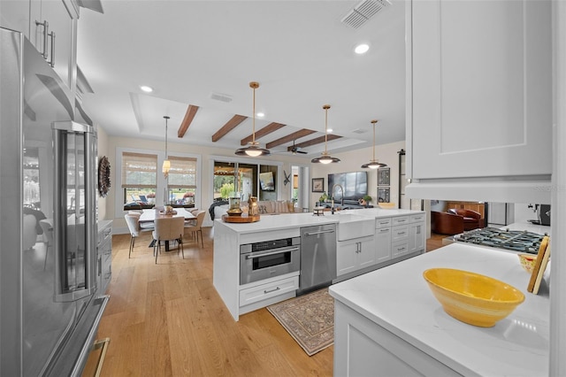 kitchen featuring white cabinetry, appliances with stainless steel finishes, and decorative light fixtures