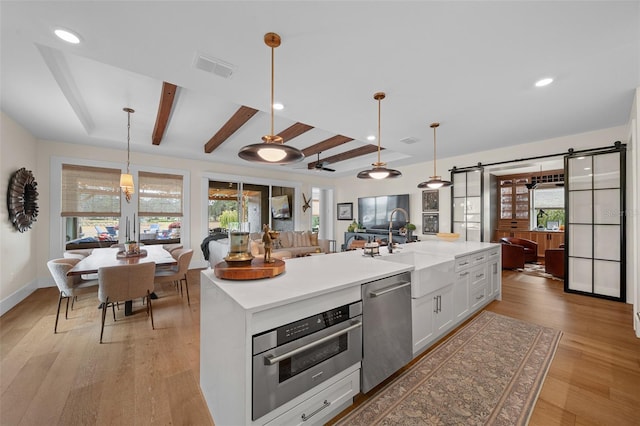 kitchen with white cabinetry, appliances with stainless steel finishes, a barn door, and hanging light fixtures