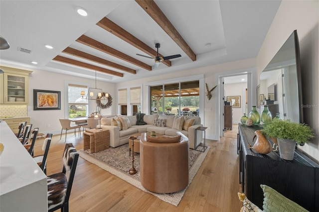 living room with beamed ceiling, ceiling fan with notable chandelier, and light hardwood / wood-style flooring