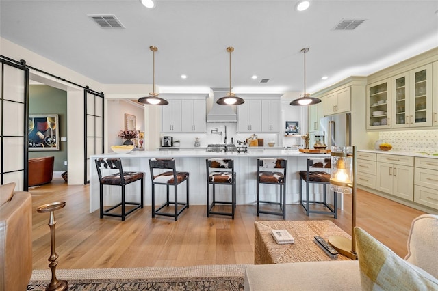 kitchen with a barn door, high quality fridge, pendant lighting, and a breakfast bar