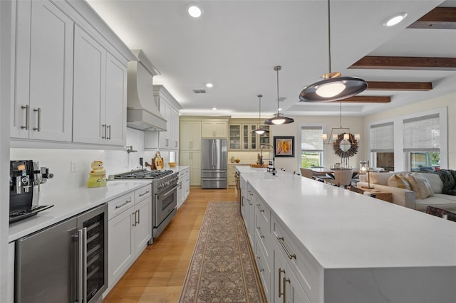 kitchen with decorative light fixtures, custom exhaust hood, stainless steel appliances, and a spacious island