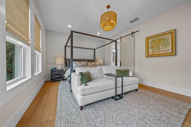 bedroom featuring a barn door and light wood-type flooring