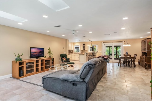 tiled living room with ceiling fan and a skylight