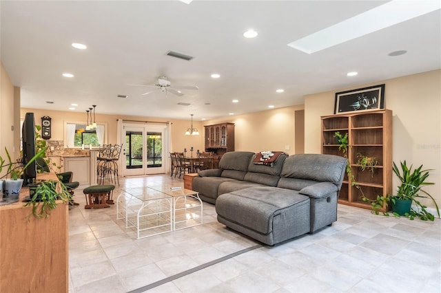 tiled living room featuring ceiling fan and a skylight