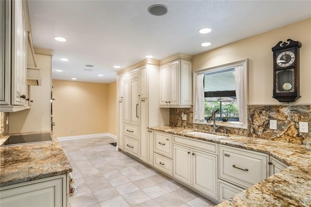 kitchen featuring black electric stovetop, decorative backsplash, sink, light stone counters, and light tile patterned floors