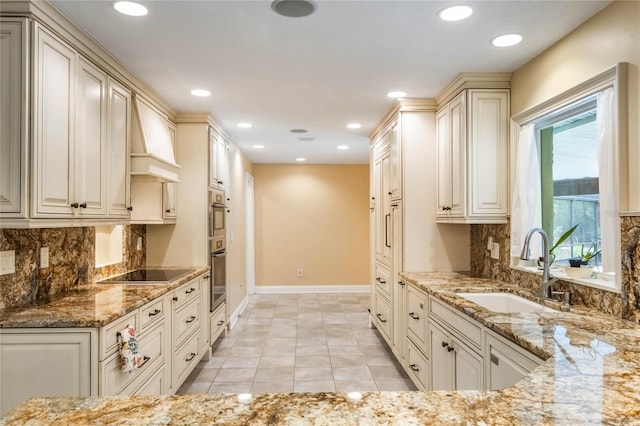 kitchen with light stone counters, sink, black electric cooktop, and custom range hood