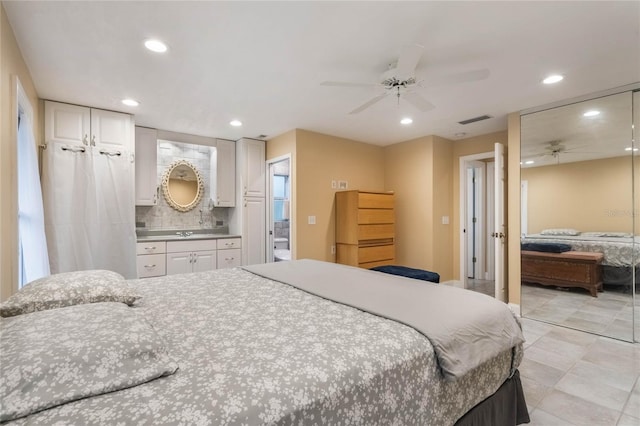 bedroom with ceiling fan, sink, and ensuite bath