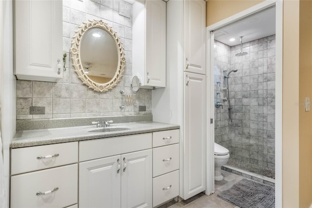 bathroom featuring tile patterned floors, vanity, decorative backsplash, toilet, and tiled shower