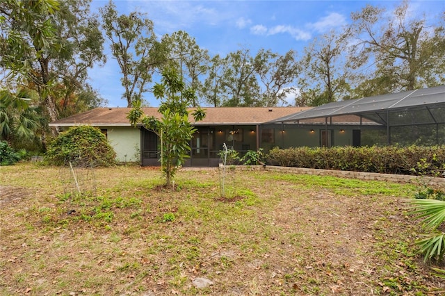 rear view of house featuring a lanai and a lawn