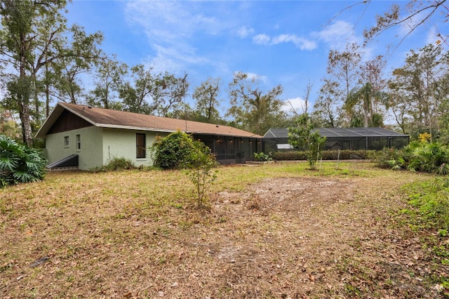 rear view of house with a lanai and a lawn