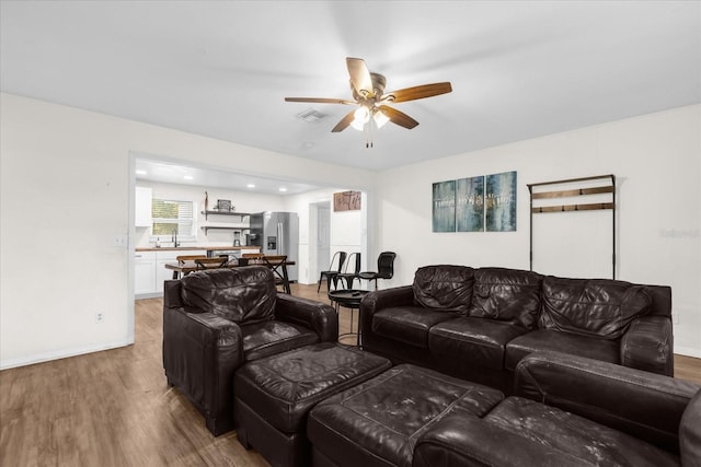 living room featuring hardwood / wood-style flooring, sink, and ceiling fan