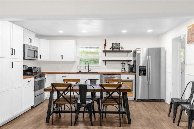 kitchen featuring white cabinetry, stainless steel appliances, sink, and light hardwood / wood-style flooring