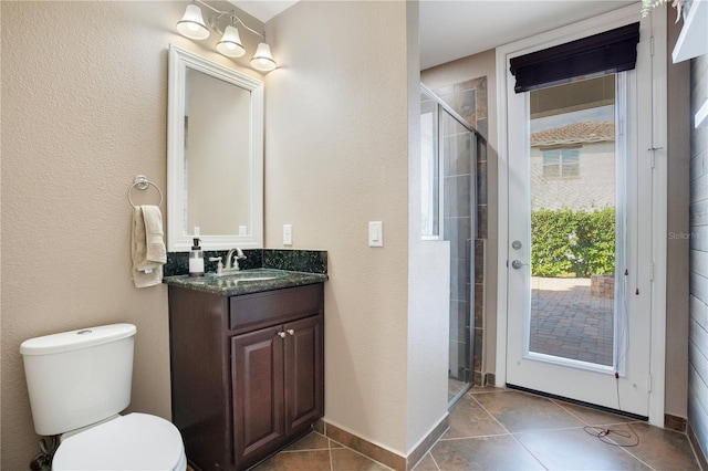 bathroom with a shower with door, vanity, tile patterned floors, and toilet