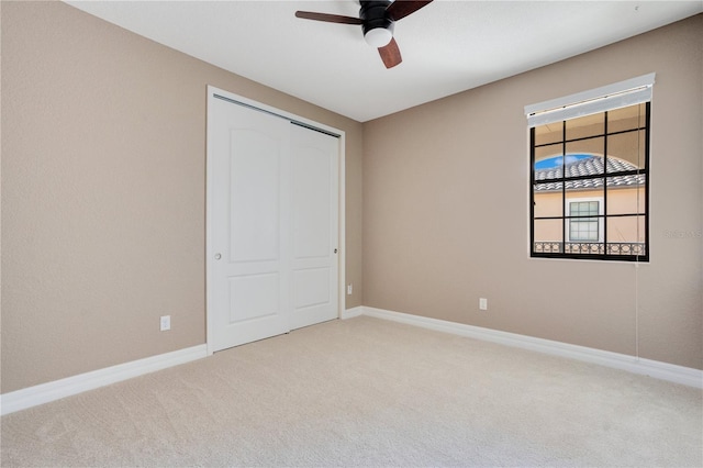 unfurnished bedroom featuring light colored carpet, ceiling fan, and a closet