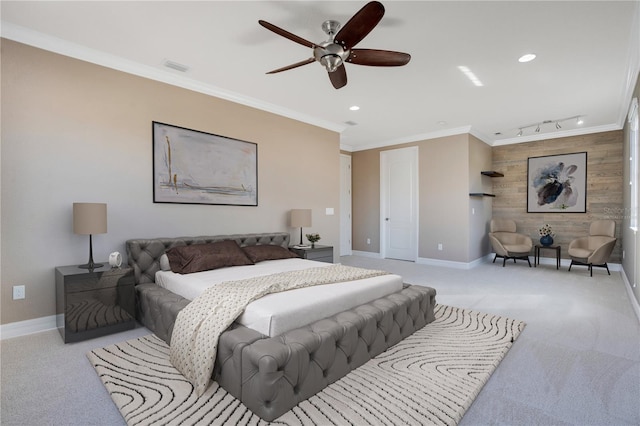 carpeted bedroom with ornamental molding, rail lighting, ceiling fan, and wood walls