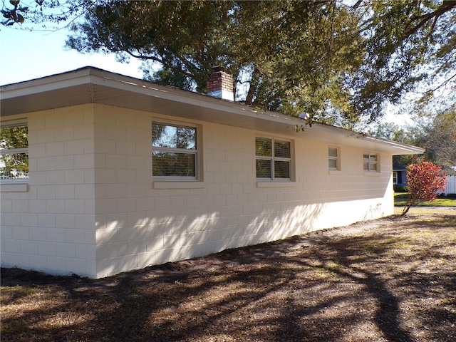 view of home's exterior featuring concrete block siding and a chimney