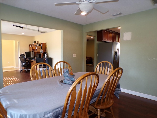 dining room with dark wood-type flooring, a ceiling fan, visible vents, and baseboards