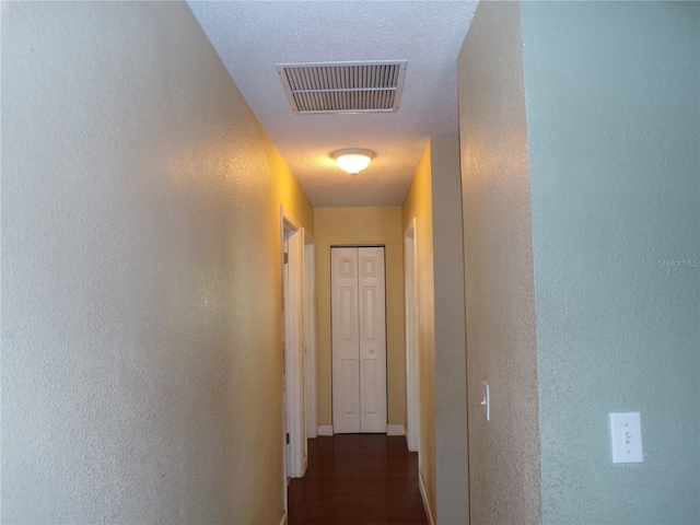 corridor featuring visible vents and a textured wall