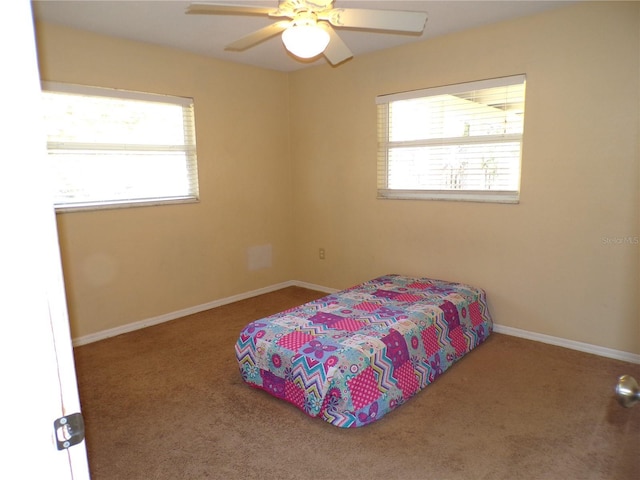 carpeted bedroom with ceiling fan and baseboards