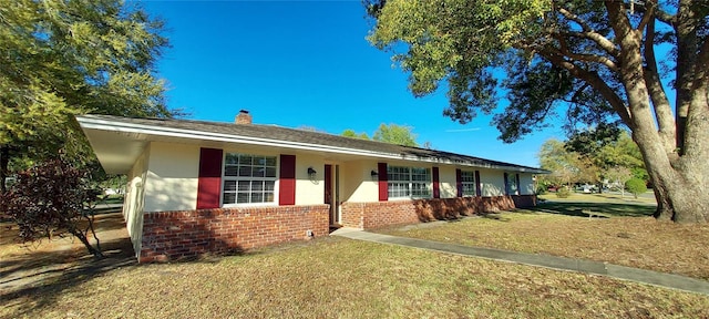 ranch-style home with brick siding, a chimney, and a front lawn