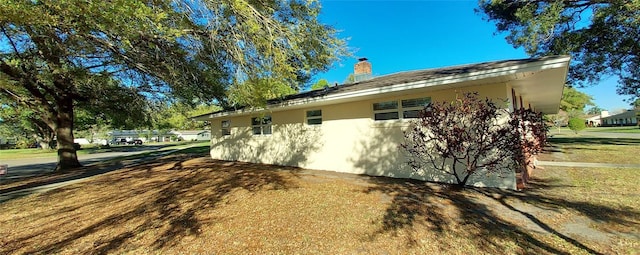 view of side of property with a chimney and stucco siding