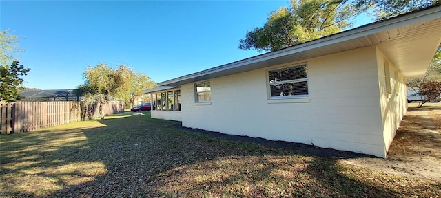 view of property exterior with a lawn, concrete block siding, and fence