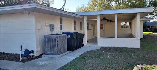 view of exterior entry with central AC unit, concrete block siding, and a ceiling fan