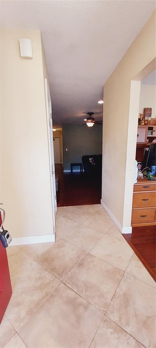 hall featuring light tile patterned floors and baseboards