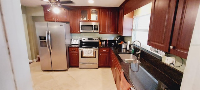 kitchen featuring ceiling fan, stainless steel appliances, a sink, dark brown cabinets, and glass insert cabinets