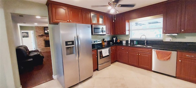 kitchen featuring a fireplace, stainless steel appliances, glass insert cabinets, a sink, and ceiling fan