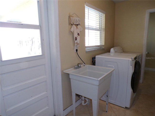 washroom featuring light tile patterned floors, laundry area, washing machine and dryer, and baseboards