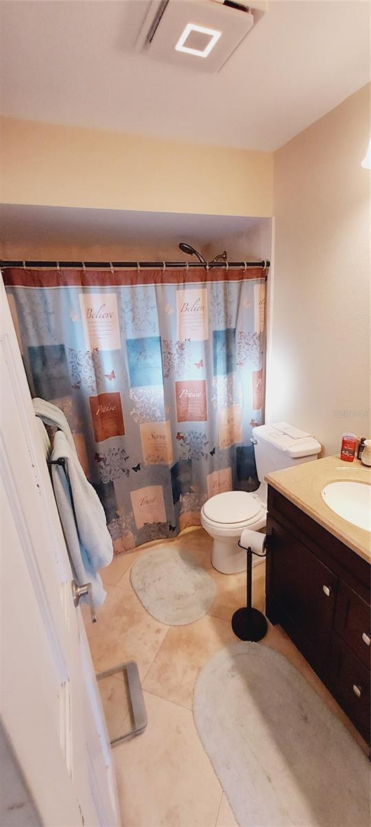 bathroom with a shower with shower curtain, tile patterned flooring, vanity, and toilet