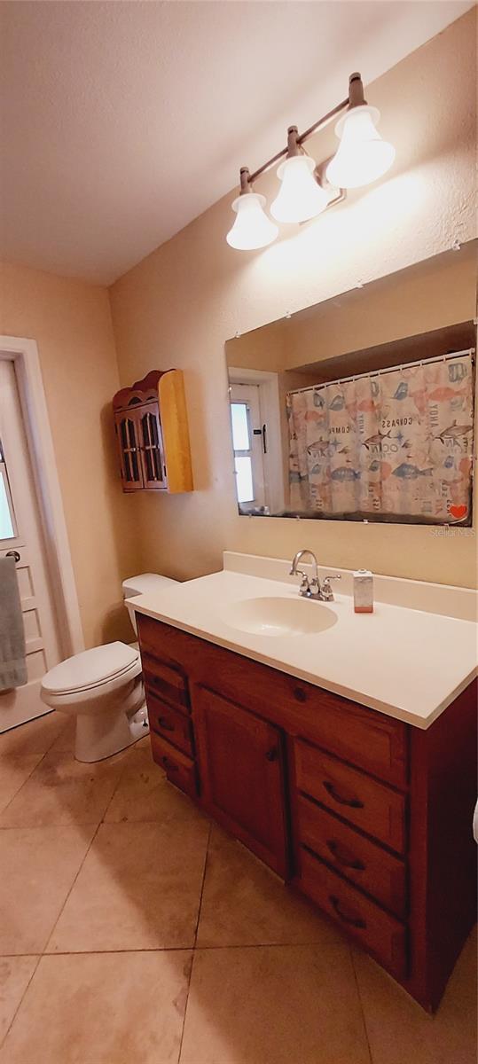 bathroom with toilet, tile patterned flooring, and vanity