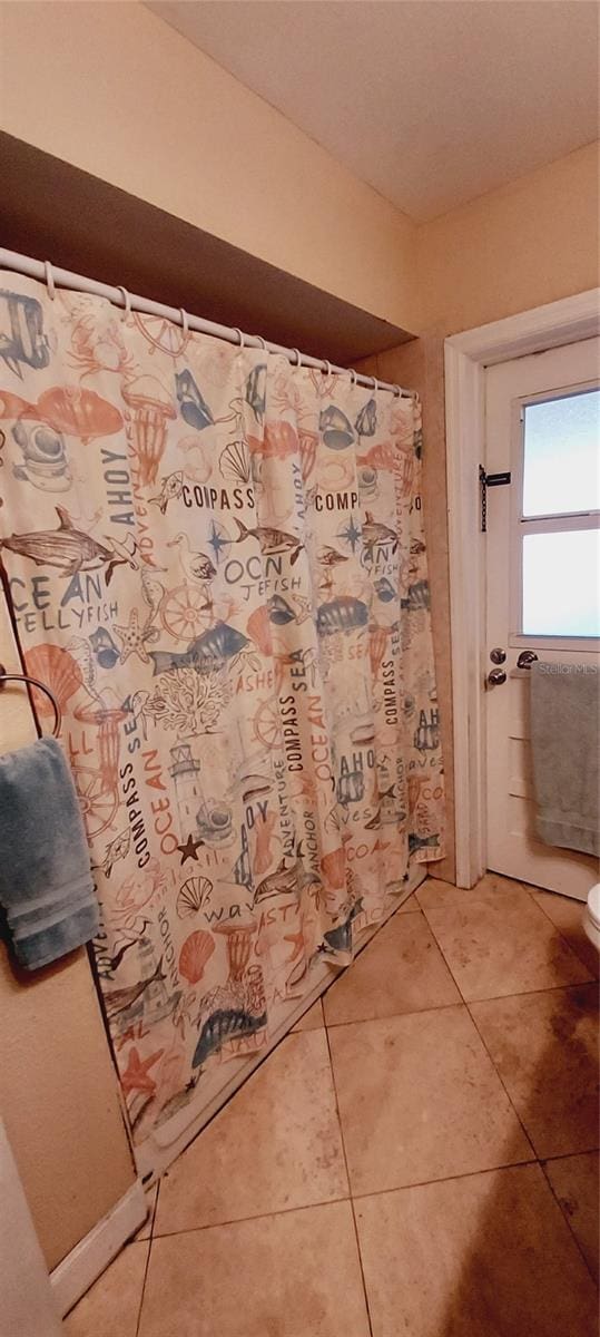 full bathroom featuring tile patterned flooring, toilet, and a shower with curtain