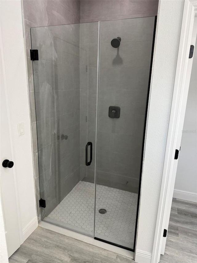 bathroom with wood-type flooring and a shower with door