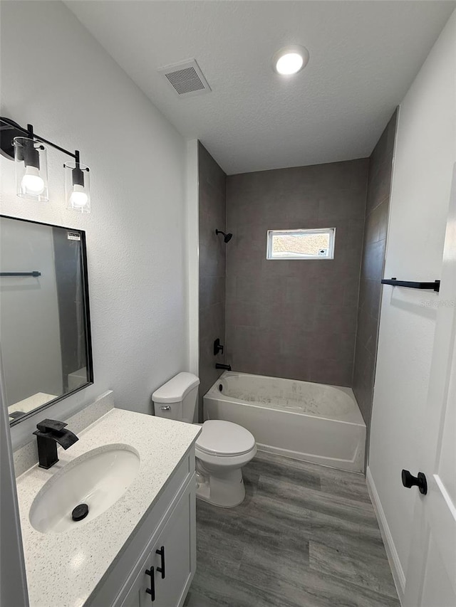 full bathroom with toilet, tiled shower / bath, wood-type flooring, and vanity