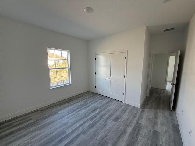 unfurnished bedroom featuring a closet and dark wood-type flooring