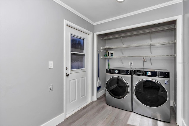 laundry room with washing machine and clothes dryer, ornamental molding, and light hardwood / wood-style flooring