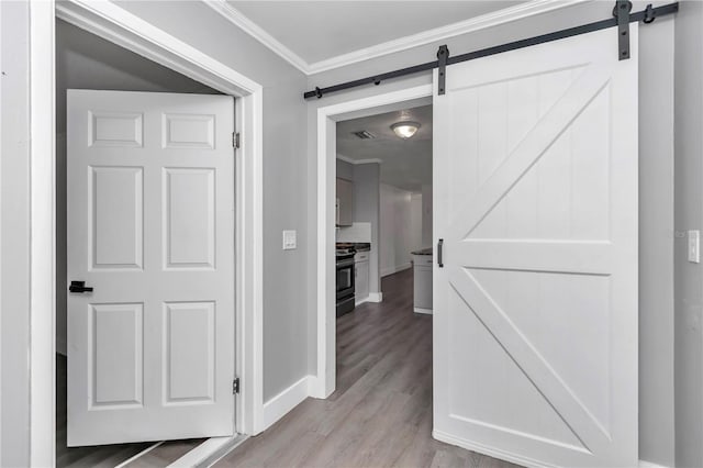 corridor with crown molding, a barn door, and light hardwood / wood-style floors