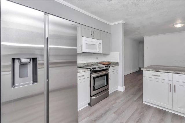 kitchen featuring a textured ceiling, light wood-type flooring, white cabinets, stainless steel appliances, and backsplash