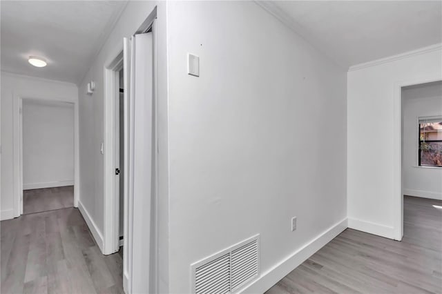 hallway with crown molding and light wood-type flooring